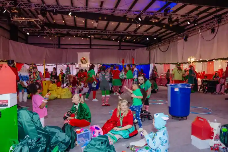 volunteers dressed as elves organizing fantasy flight event and handing out christmas treats to children