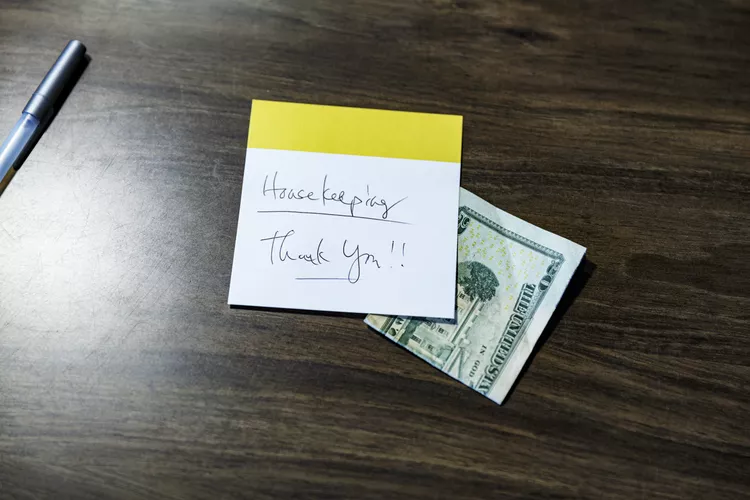 hotel guest room bedside table with tip money and handwritten thank you note