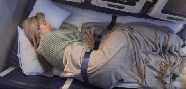 passenger lying across economy row sleeping with airline mattress cushion long haul flight