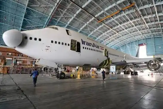 Aircraft maintenance engineers servicing Iran Air Boeing 747SP engines inside hangar