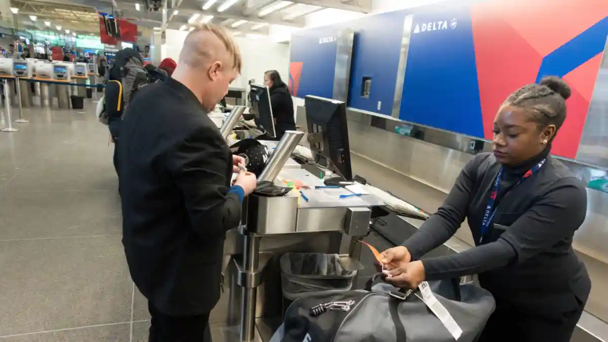 Delta Air Lines passengers checking luggage at airport baggage counter United States