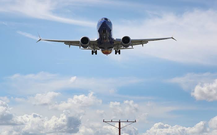 Boeing 737 MAX 8 on climb-out with jet bridge in background